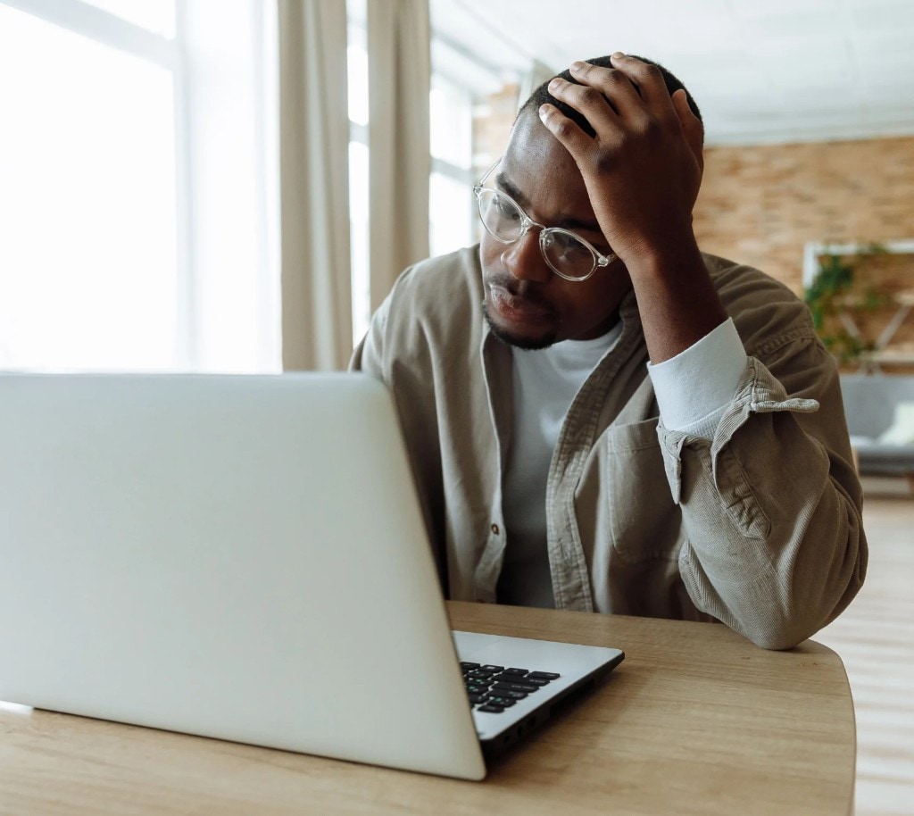 Small business owner looking frustrated while doing bookkeeping on a laptop